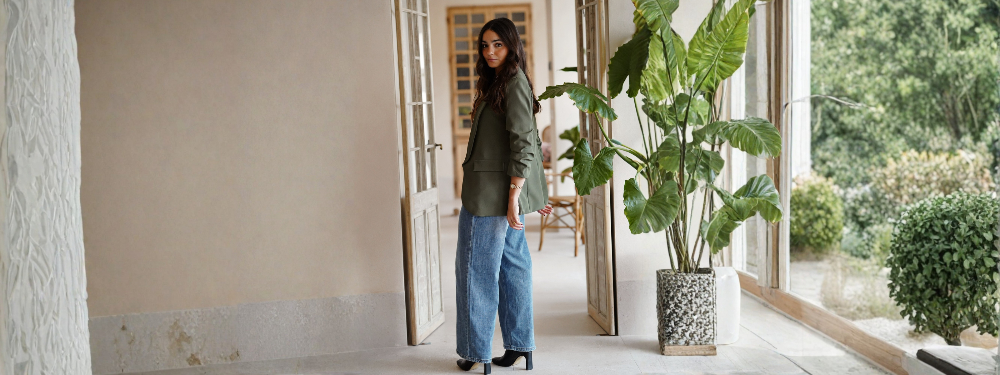 Mujer con pantalones elegantes para mujer en un entorno luminoso con plantas y decoración natural.