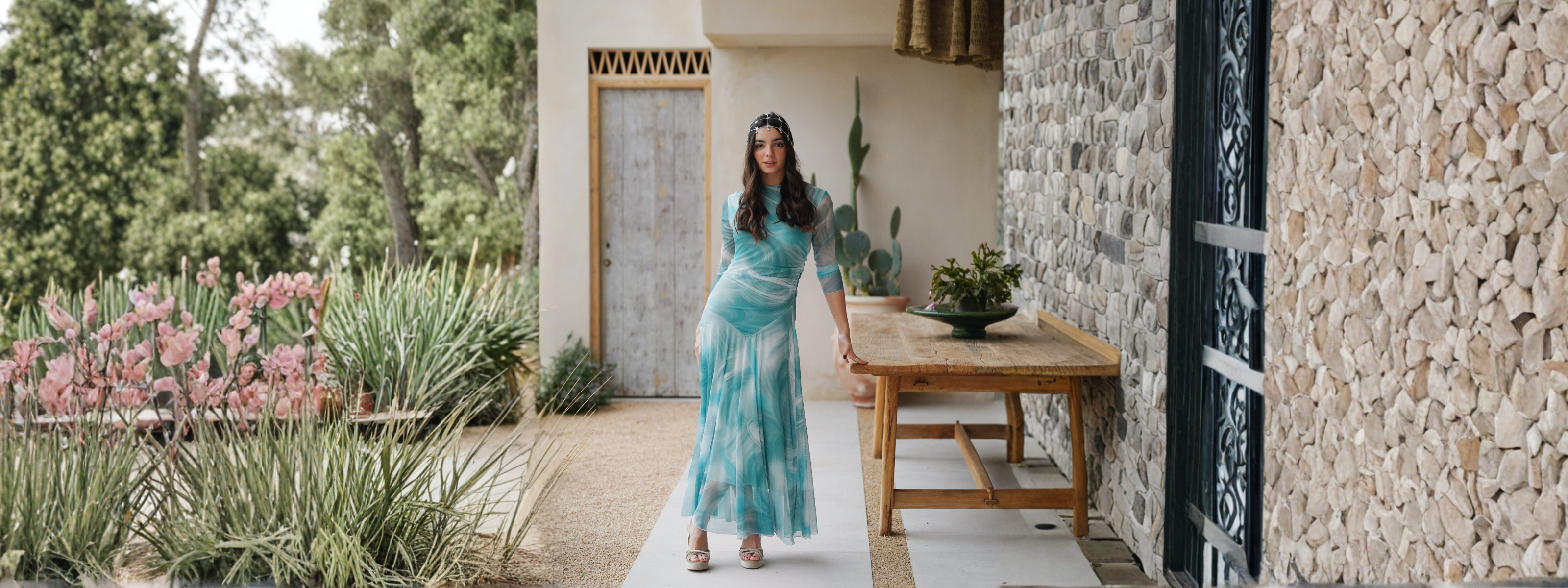 Mujer con vestido de fiesta de temporada caminando en un jardín, invitadas LowCost en Mariquita Trasquilá.