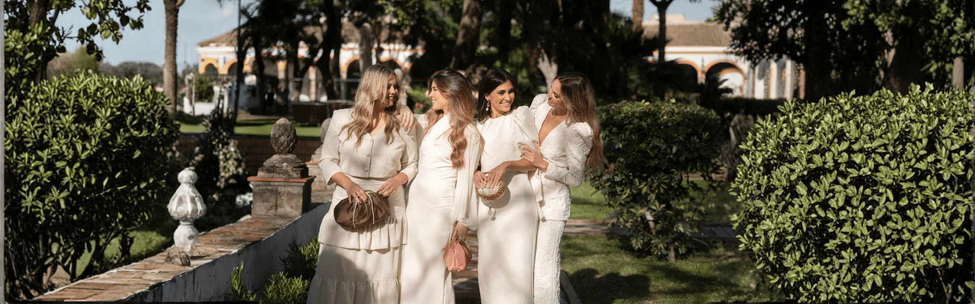 Cuatro mujeres luciendo vestidos en un evento al aire libre, invitada de boda en un entorno elegante.