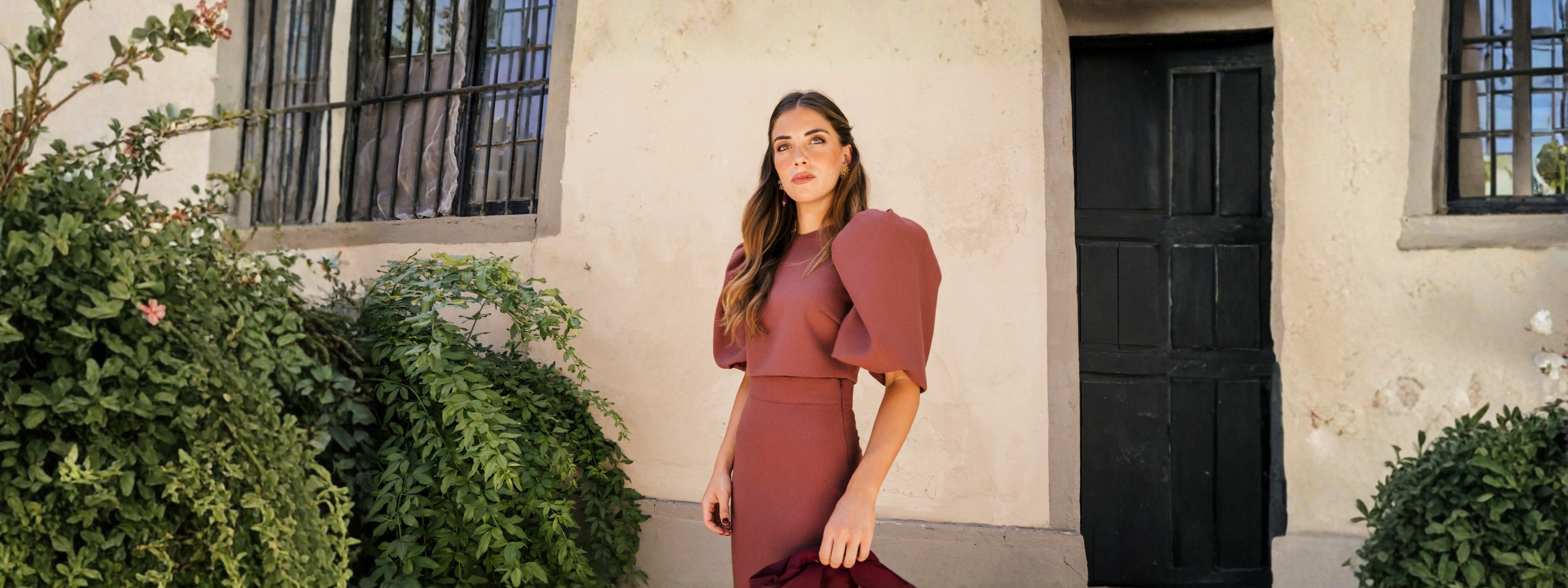 Conjunto de Invitada en Mariquita Trasquilá, mujer elegante en un entorno natural con flores blancas.
